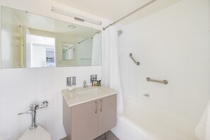 Casa de banho moderna com lavatório, espelho e chuveiro.