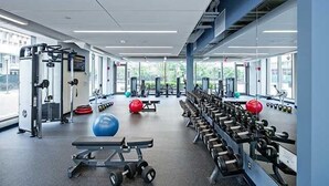 A gym with exercise equipment, benches, and dumbbells. - Modern 1 Bed Apartment in Central Back Bay, Boston (Boston)