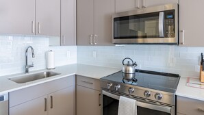 A modern kitchen with stainless steel appliances, a sink, and light-colored cabinets. - Modern 1 Bed Apartment in Central Back Bay, Boston (Boston)