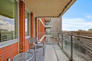 Enjoy the city view from this balcony with a chair and table.