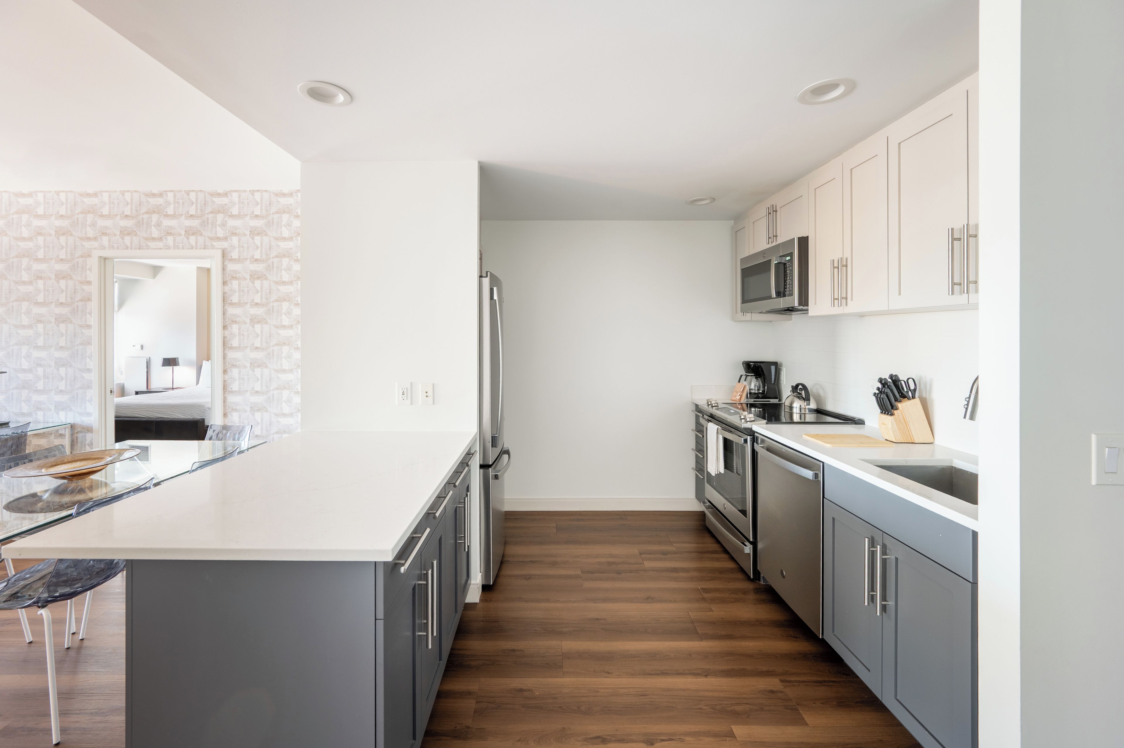 A modern kitchen with a central island, stainless steel appliances, and grey cabinetry.