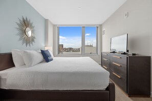 A modern bedroom with a large bed, a dresser, and a TV.