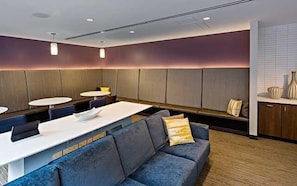 A modern hotel lobby with a seating area, a reception desk, and a counter.