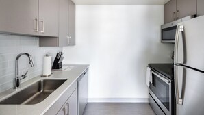 A modern kitchen with stainless steel appliances, a built-in microwave, and a dishwasher. - Spacious Apartment in Luxury Back Bay Building (Boston)
