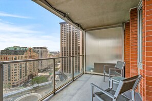 A balcony with a view of a cityscape, including high-rise buildings and a bridge.
