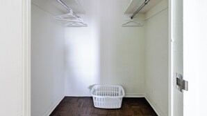 A laundry room with a white laundry basket and two white wall-mounted drying racks. - Spacious Apartment in Luxury Back Bay Building (Boston)