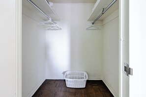A laundry room with a white laundry basket and two white wall-mounted drying racks.