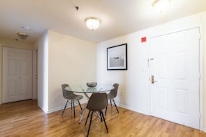 Un comedor con mesa de vidrio, cuatro sillas e imagen enmarcada en la pared.