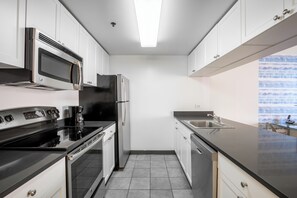 A modern kitchen with white cabinets, stainless steel appliances, and a black countertop.