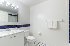 Un baño con lavabo blanco, inodoro y espejo con iluminación.