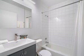 Une salle de bain moderne avec un lavabo blanc, un miroir et des toilettes.