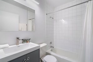 A modern bathroom with a white sink, mirror, and toilet.
