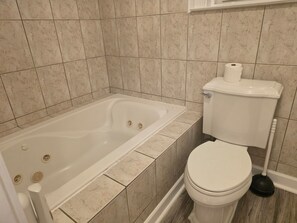 Ein Badezimmer mit Badewanne, Toilette und einem Pömpel.