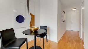 Un intérieur moderne avec une table ronde, deux chaises noires, un bol doré et des œuvres d’art abstraites accrochées au mur.