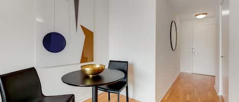 A modern interior with a round table, two black chairs, a gold bowl, and abstract wall art.