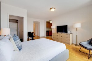 Hotellihuone, jossa on suuri sänky, televisio, työpöytä ja tuoli.