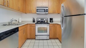 Une cuisine moderne dotée de meubles en bois, d’un réfrigérateur en acier inoxydable, d’un four à micro-ondes, d’une cuisinière et d’un lave-vaisselle.