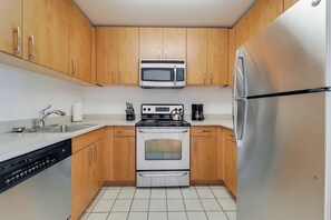 Una cocina moderna con armarios de madera, un refrigerador de acero inoxidable, un microondas, una estufa y un lavavajillas.