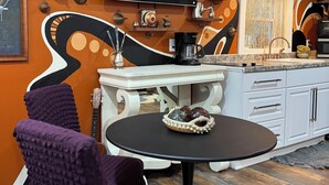 A modern kitchen with a TV mounted above the counter, a coffee maker, and decorative items on the wall.