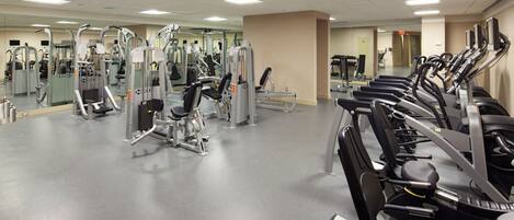 A gym with various exercise machines, mirrors, and a clean, well-lit environment.