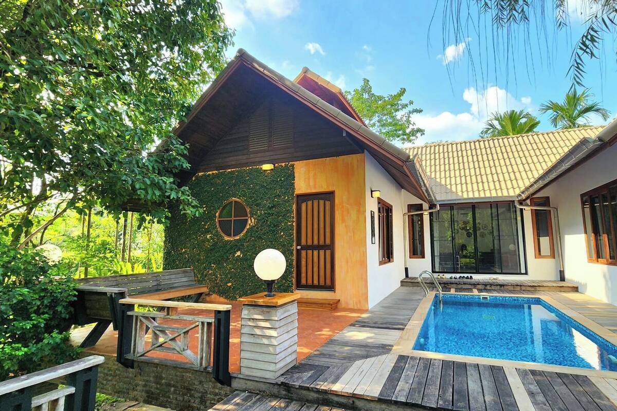 Una villa moderna con piscina, terraza de madera y porche cubierto.
