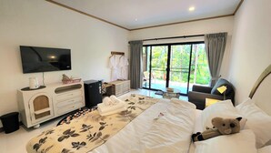 Una habitación de hotel moderna con una cama grande, un televisor, una mesita y vistas al exterior.