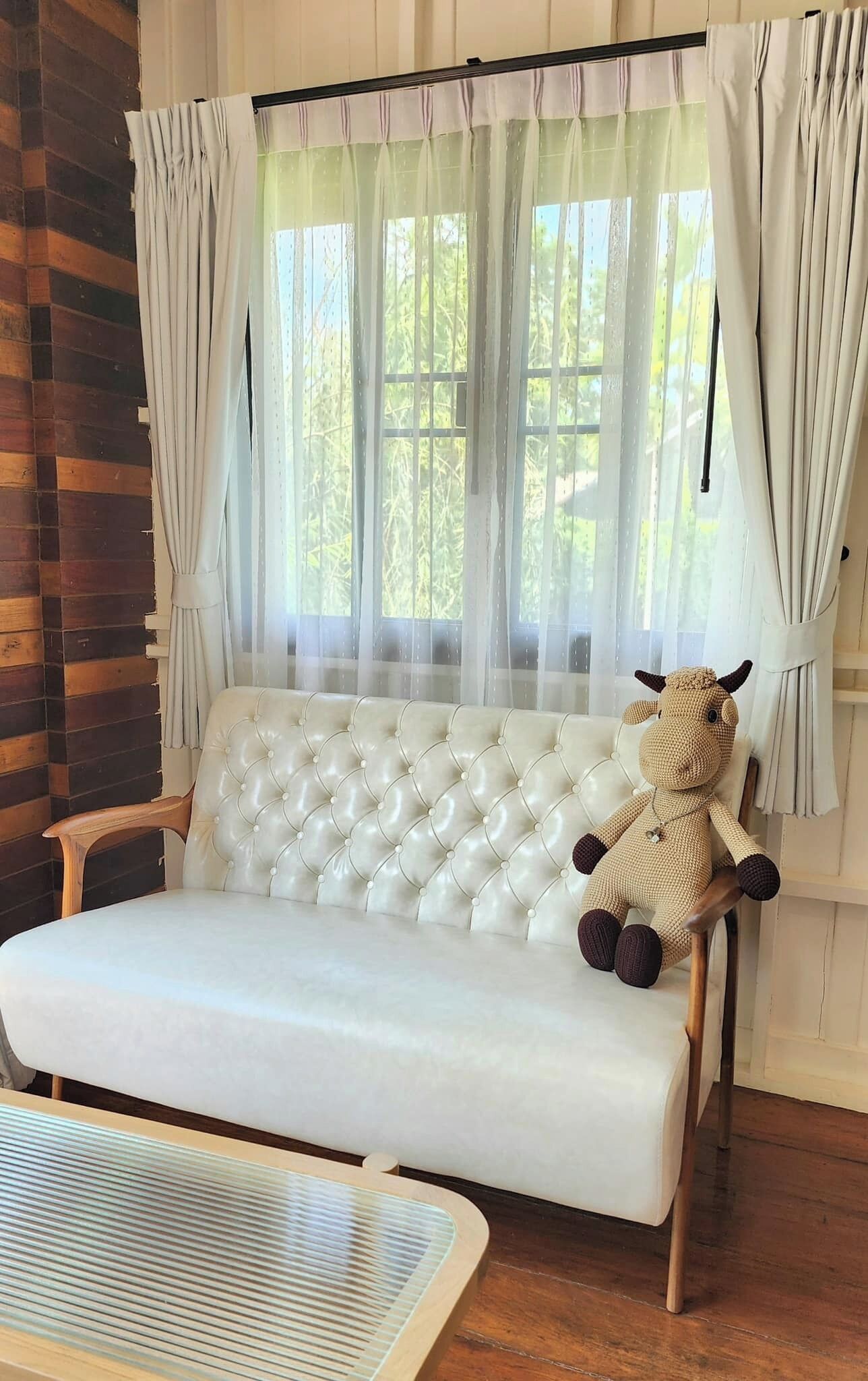 A cozy room with a white sofa, a wooden bench, and a stuffed animal.