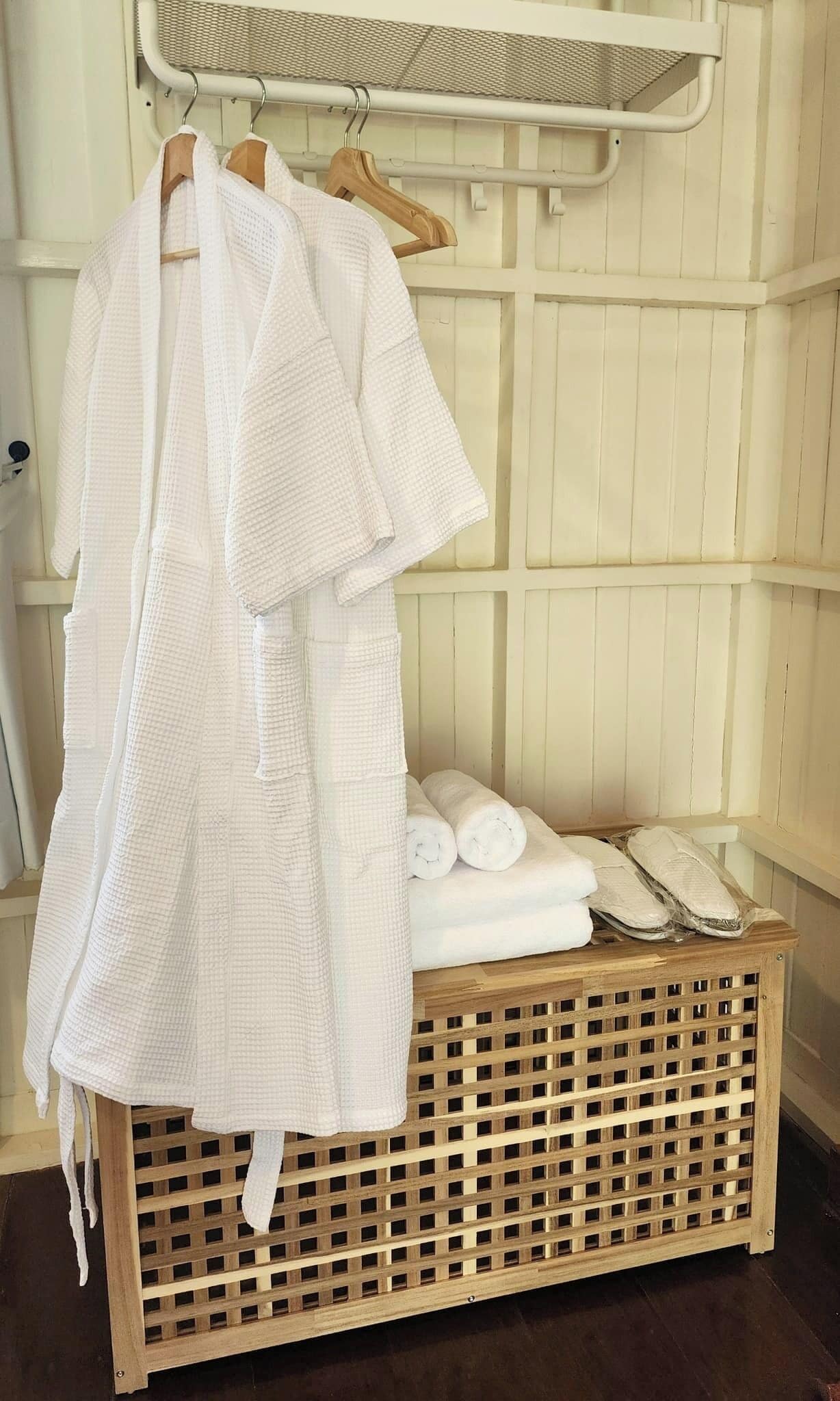 A wooden bench with a woven basket and a stack of white towels.