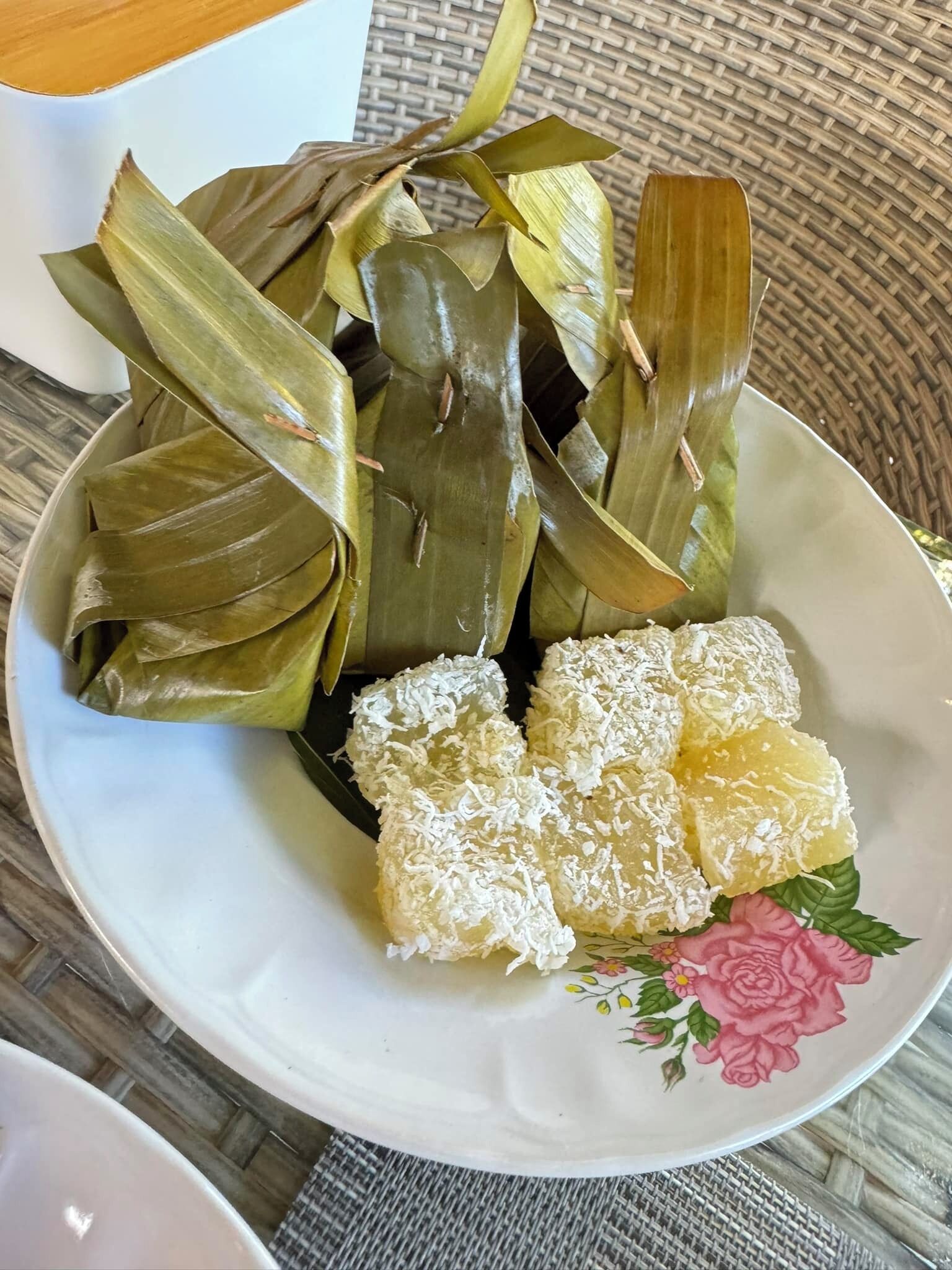 Un plato con comida envuelta en hojas y cubierta de coco rallado.