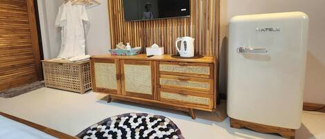 A room with a wooden cabinet, a white refrigerator, a television mounted on a wooden wall, and a wicker basket.