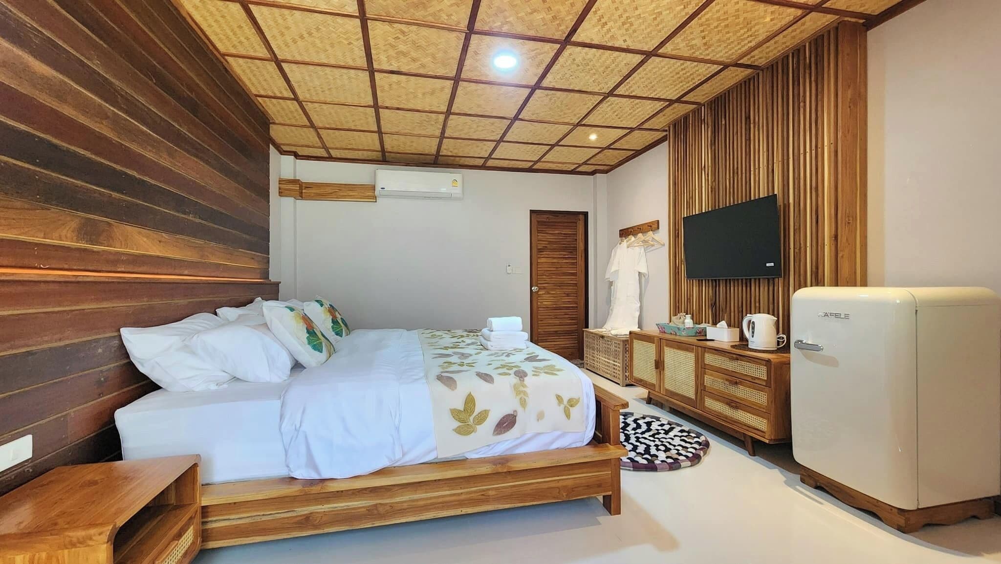 A bedroom with a wooden bed, a television, a refrigerator, and a wooden wardrobe.