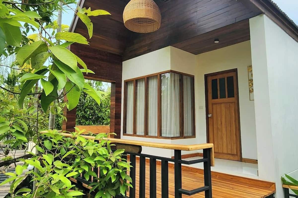 Una terraza de madera con bancos, una lámpara colgante y una puerta con ventanas.
