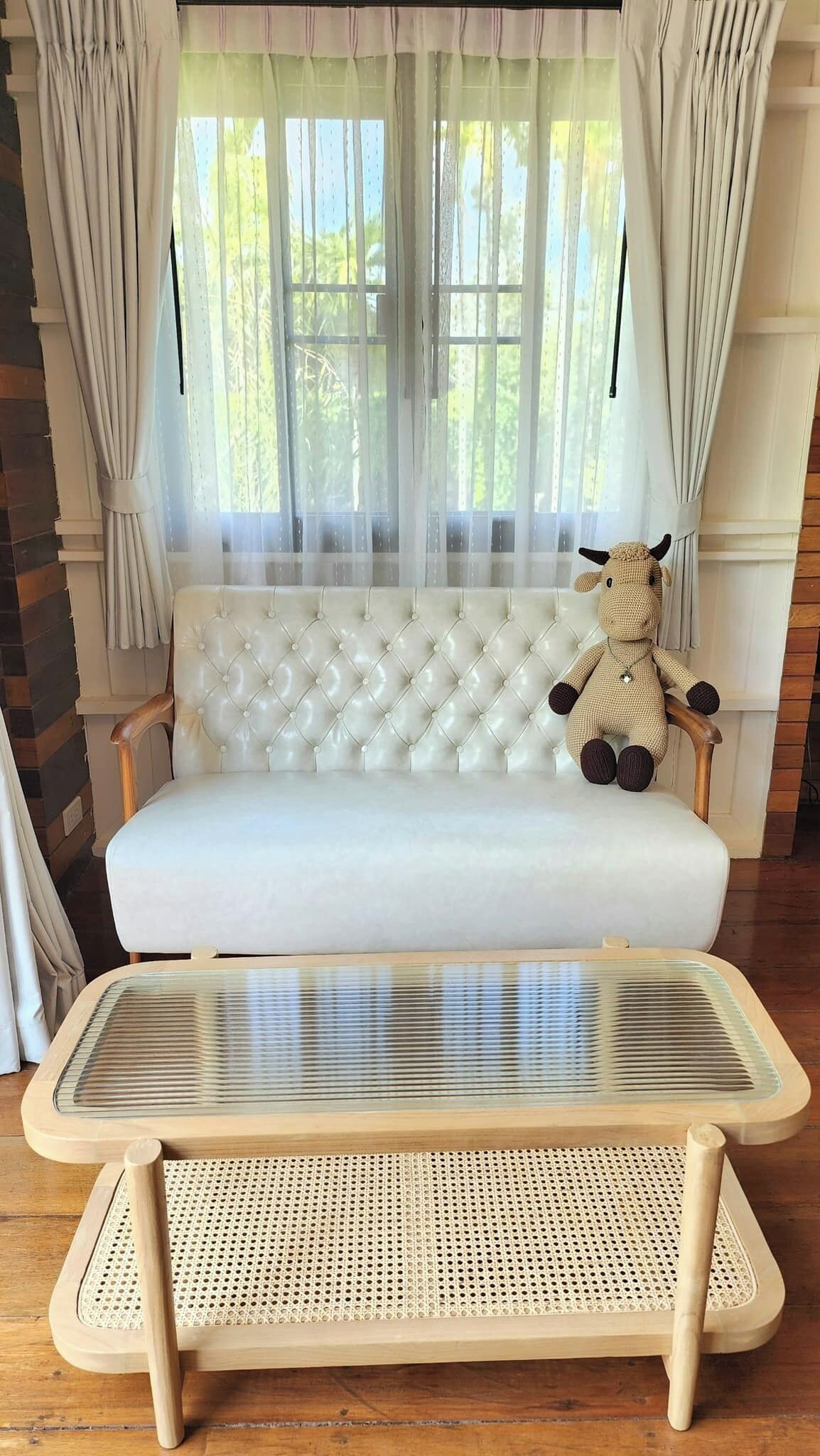 A white sofa with a tufted backrest and a woven rattan table in front.