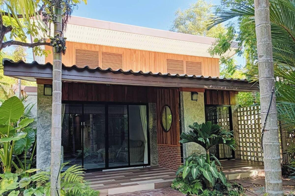 Una casa moderna con fachada de madera, amplios ventanales de vidrio y un camino de piedra que lleva a la entrada.