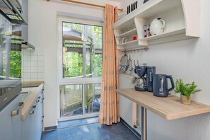 Eine Küche mit Fenster, Heizkörper, Kaffeemaschine und Pflanze.