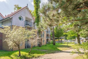 Un edificio residencial con techo de tejas rojas, balcón y un pequeño ventanal circular.