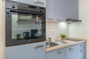 A modern kitchen with a built-in oven, a sink, and cabinets. - Cozy vacation apartment in Koserow with sea view - only 50 m to the beach! - (Koserow)