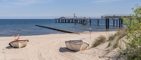 Een strand met twee boten, een steiger en een heldere lucht.