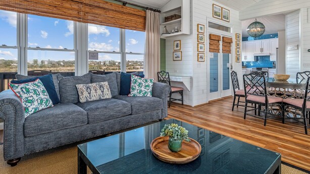 A spacious living room with a grey sofa, a glass coffee table, and a view of the outdoors. - "Paradise Palms" 3 Bedroom 3.5 Bath Second Row Home! (Supply)