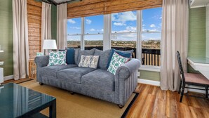 A living room with a grey sofa, patterned cushions, a glass coffee table, and a view of a landscape through large windows. - "Paradise Palms" 3 Bedroom 3.5 Bath Second Row Home! (Supply)