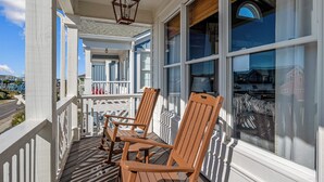 A porch with wooden chairs and a railing, large windows, and a hanging lantern. - "Paradise Palms" 3 Bedroom 3.5 Bath Second Row Home! (Supply)