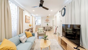 A modern living room with a sofa, coffee table, TV, and ceiling fan.