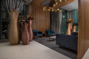 A modern lobby with large vases, a blue sofa, and a wooden slatted wall. - Downtown Retreat | Tribeca | Roof Deck (New York)