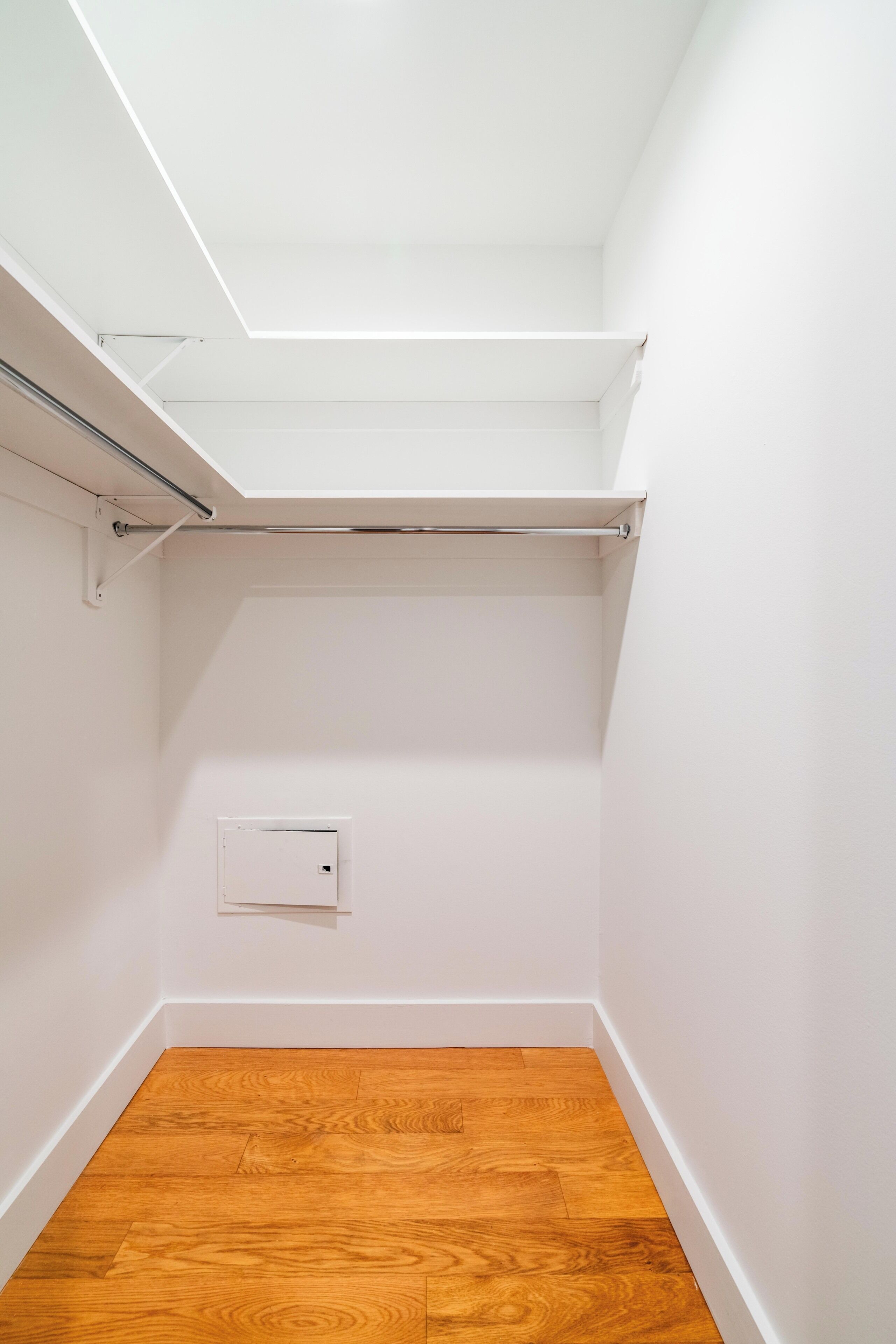 Une petite pièce vide aux murs blancs, avec un plancher en bois et une lucarne.