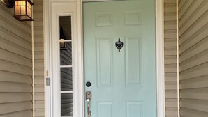 Une porte d’entrée bleu clair, dotée d’une petite fenêtre et d’une sonnette.