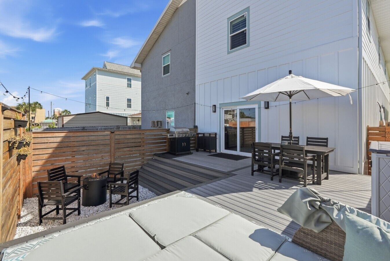 A backyard with a barbecue, outdoor seating, and a wooden deck.