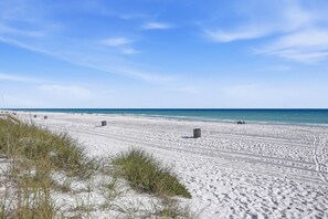 Une vaste plage de sable, bordée de dunes, et un ciel bleu azur.