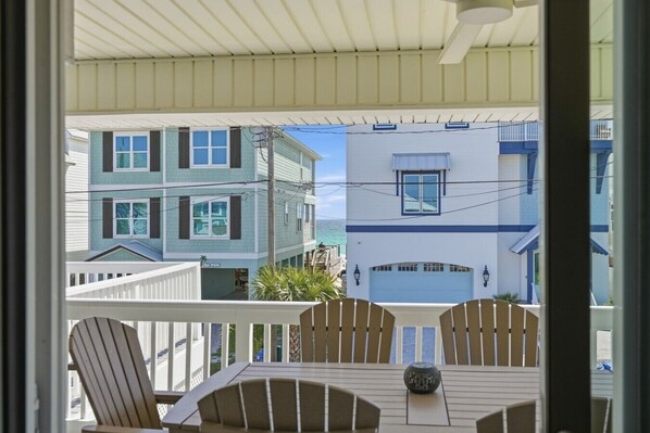 A balcony with a table and chairs, overlooking a coastal area with buildings.
