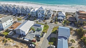 A coastal residential area with beachfront properties, including houses with sloped roofs and a beach in the background.
