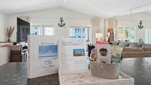 A reception area with a welcome sign, a brochure stand, and a view of the living room.